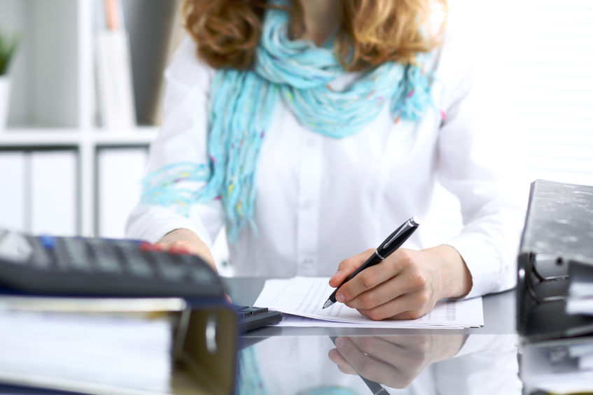 Une femme assise à un bureau entrain d'écrire